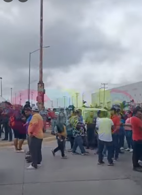 Obreros de Tridonex a punto de colocar las banderas rojinegras afuera de la maquiladora.